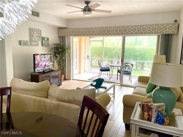 living room with ceiling fan, light hardwood / wood-style flooring, a healthy amount of sunlight, and a textured ceiling