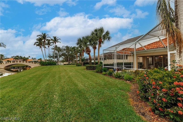 view of yard featuring glass enclosure and a water view