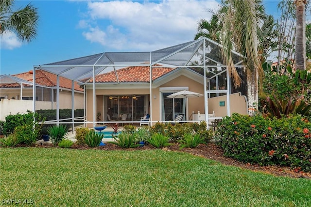 rear view of property with a lanai and a yard