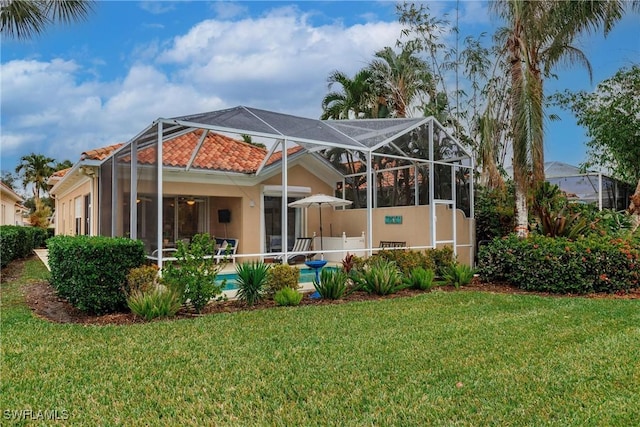 rear view of house with glass enclosure and a yard