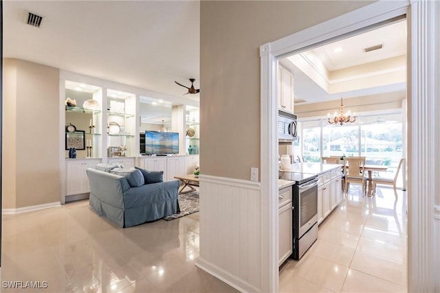 kitchen featuring ceiling fan with notable chandelier, pendant lighting, light tile patterned floors, white cabinets, and stainless steel electric range