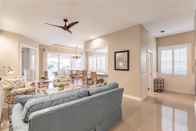 living room featuring ceiling fan with notable chandelier and plenty of natural light