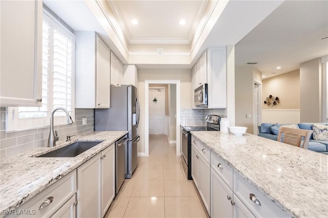 kitchen with white cabinets, sink, light tile patterned floors, appliances with stainless steel finishes, and light stone counters