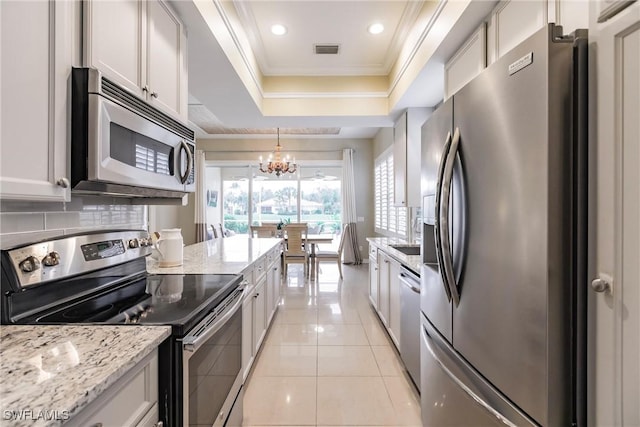 kitchen featuring light tile patterned floors, white cabinetry, stainless steel appliances, and hanging light fixtures