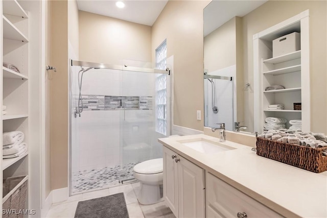 bathroom with tile patterned floors, vanity, a shower with door, built in features, and toilet