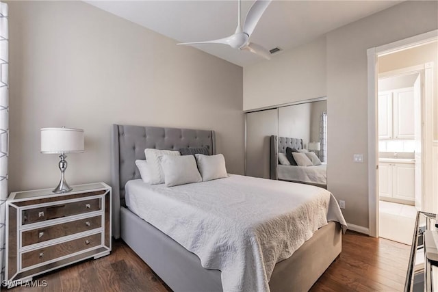 bedroom with a closet, ensuite bath, ceiling fan, and dark wood-type flooring