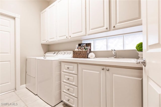 washroom with cabinets, light tile patterned floors, washing machine and dryer, and sink