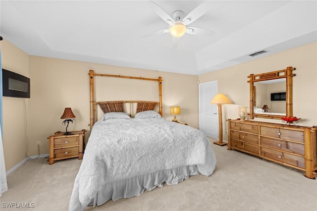 bedroom with ceiling fan, a raised ceiling, and light colored carpet