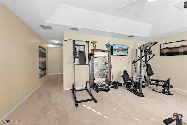 workout room with a raised ceiling and light carpet