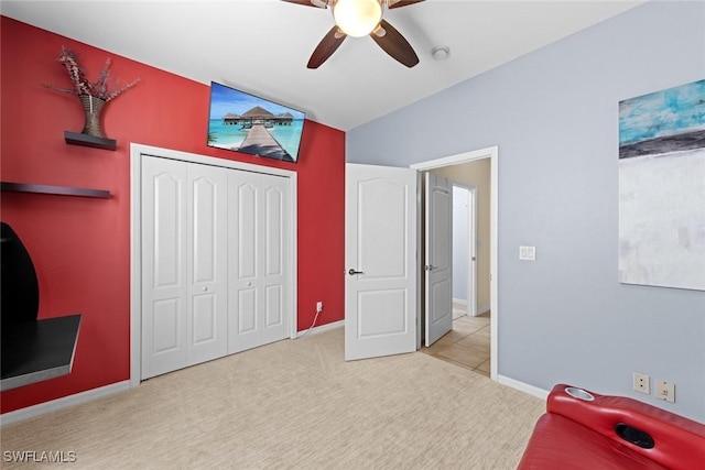 carpeted bedroom with a closet, vaulted ceiling, and ceiling fan