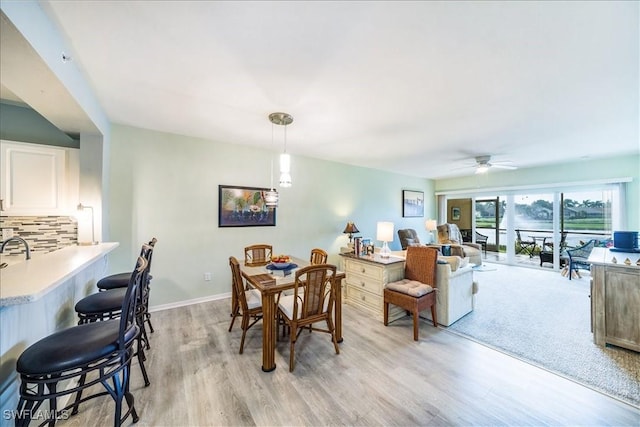 dining space with ceiling fan and light hardwood / wood-style flooring