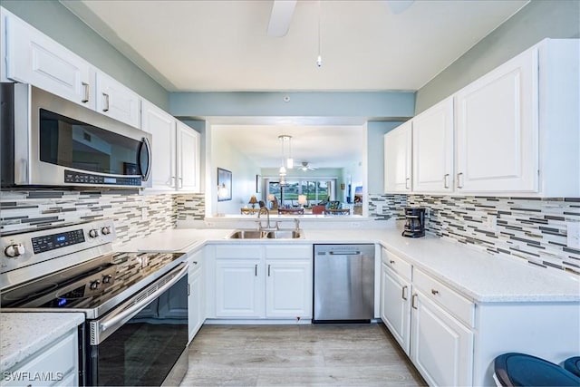 kitchen featuring sink, hanging light fixtures, tasteful backsplash, white cabinets, and appliances with stainless steel finishes