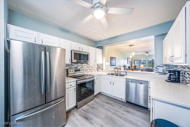 kitchen featuring sink, stainless steel appliances, tasteful backsplash, decorative light fixtures, and white cabinets