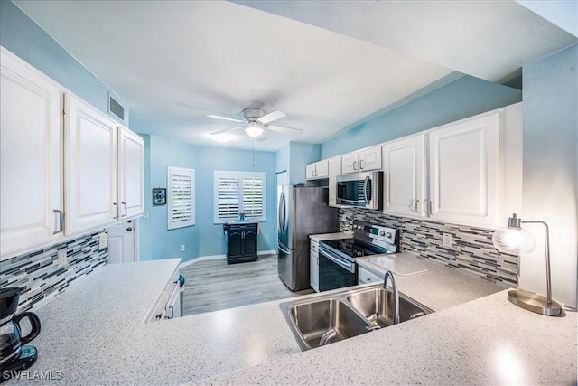 kitchen with appliances with stainless steel finishes, backsplash, ceiling fan, sink, and white cabinets