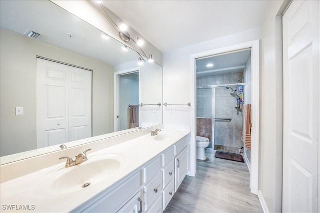 bathroom with hardwood / wood-style flooring, vanity, toilet, and walk in shower