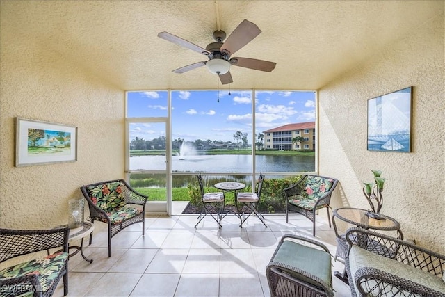 sunroom with ceiling fan and a water view