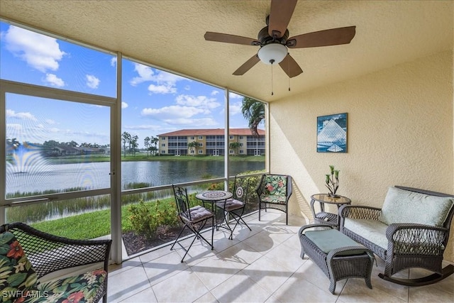 sunroom featuring ceiling fan and a water view