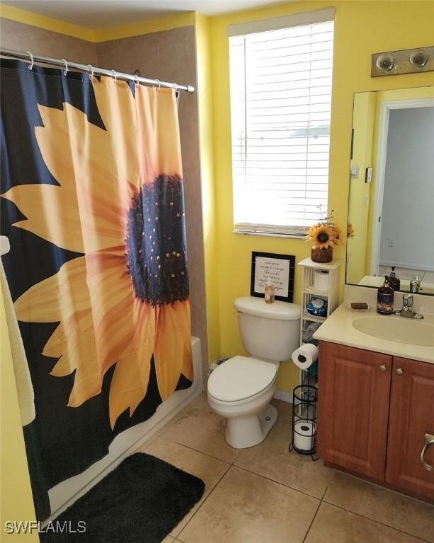 full bathroom featuring tile patterned floors, shower / tub combo with curtain, vanity, and toilet