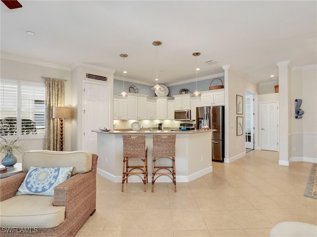 kitchen featuring decorative light fixtures, stainless steel appliances, an island with sink, a breakfast bar, and crown molding