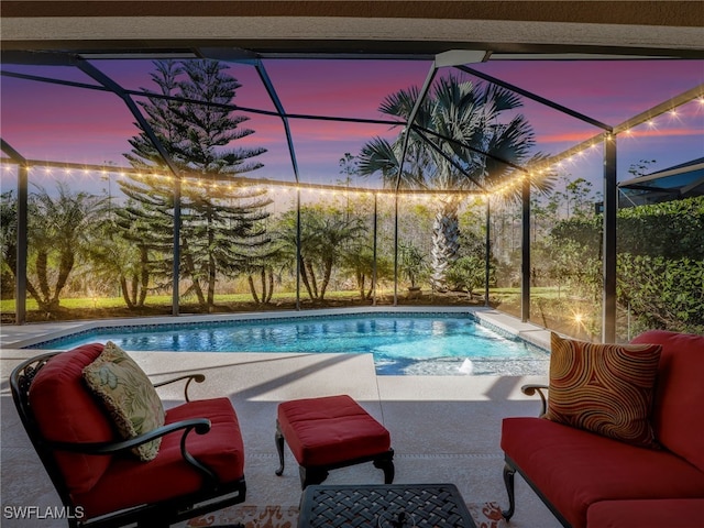 pool at dusk with a patio area and glass enclosure