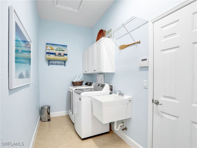 clothes washing area with cabinets, washing machine and dryer, and light tile patterned floors