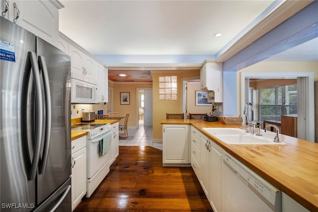 kitchen with white cabinets, white appliances, butcher block countertops, and sink