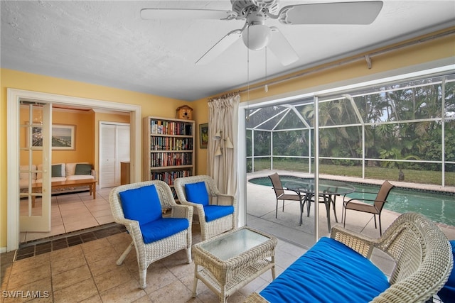 interior space with an outdoor hangout area, glass enclosure, and ceiling fan