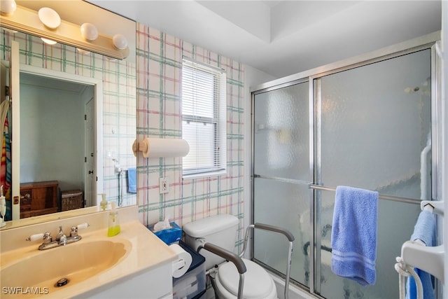 bathroom featuring vanity, toilet, and a shower with shower door