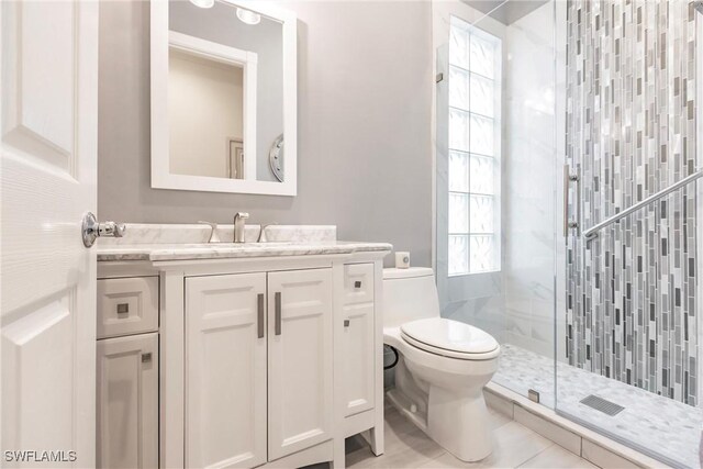 bathroom featuring tile patterned flooring, vanity, toilet, and a shower with door