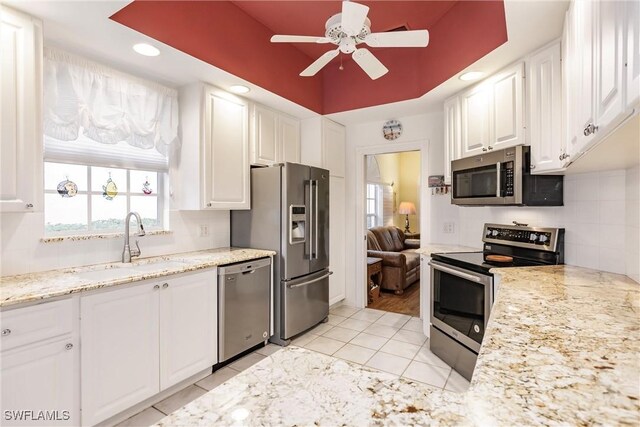 kitchen with sink, tasteful backsplash, a raised ceiling, appliances with stainless steel finishes, and white cabinets