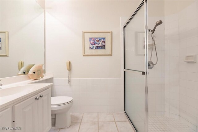 bathroom with tile patterned floors, toilet, tile walls, and a shower with shower door