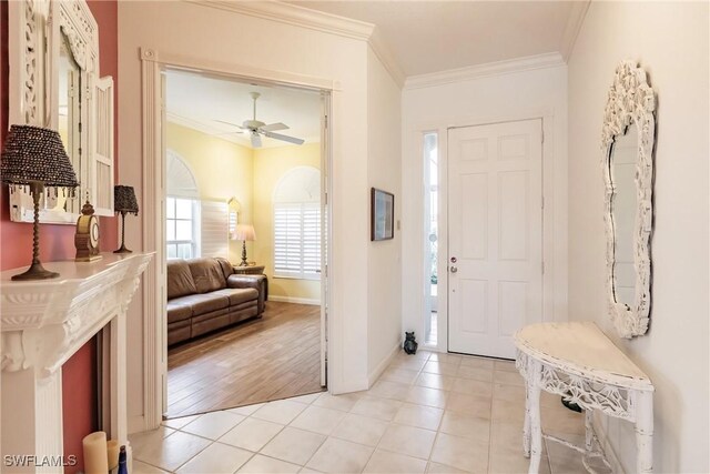 entryway with ceiling fan, light tile patterned floors, and crown molding