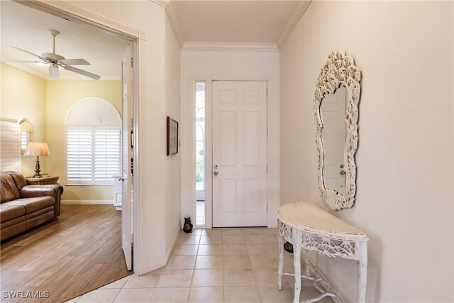 tiled foyer entrance featuring ceiling fan and crown molding