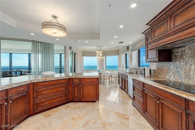 kitchen featuring a tray ceiling, black electric stovetop, a water view, and hanging light fixtures