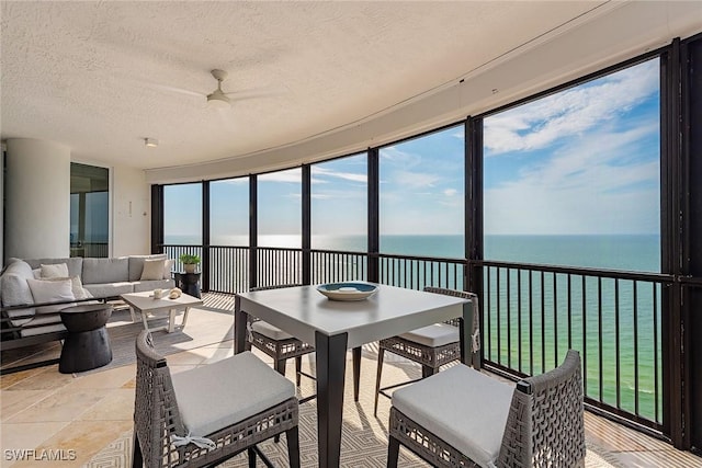 sunroom featuring ceiling fan and a water view