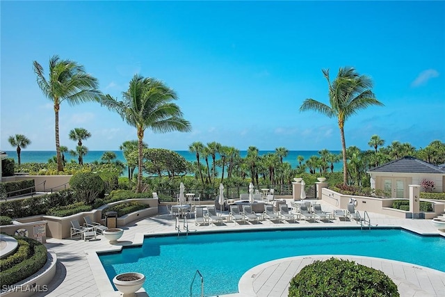 view of pool featuring a water view and a patio