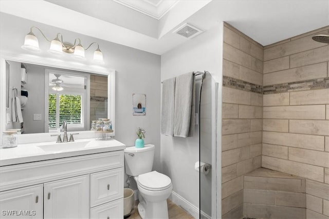 bathroom with ceiling fan, vanity, toilet, and tiled shower