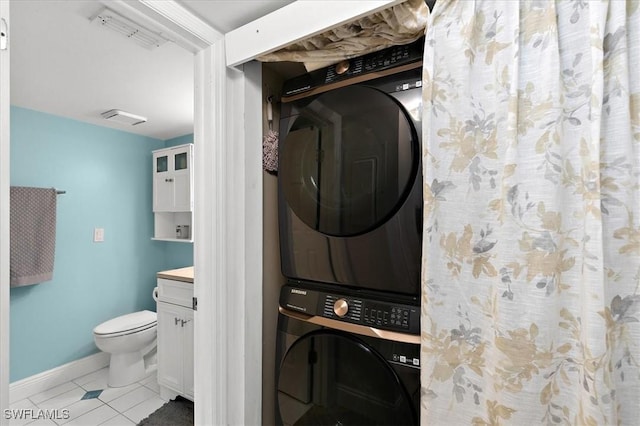 washroom with stacked washing maching and dryer and light tile patterned floors