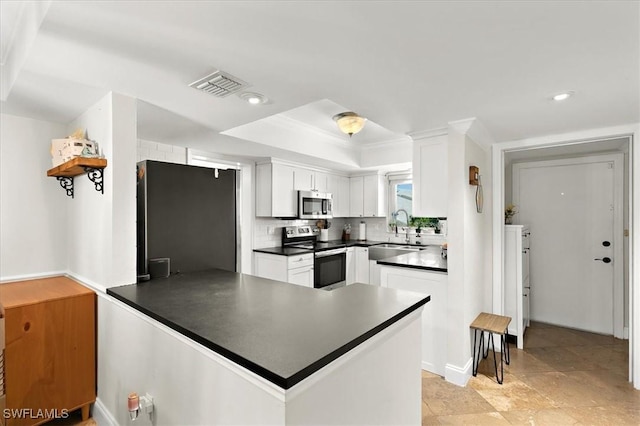 kitchen featuring white cabinetry, stainless steel appliances, decorative backsplash, sink, and kitchen peninsula