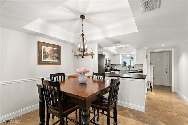 dining space featuring sink, crown molding, a raised ceiling, and a notable chandelier