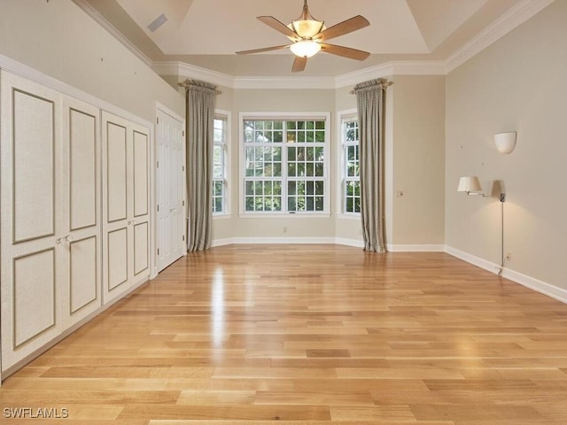 unfurnished bedroom featuring ornamental molding, two closets, ceiling fan, and light wood-type flooring