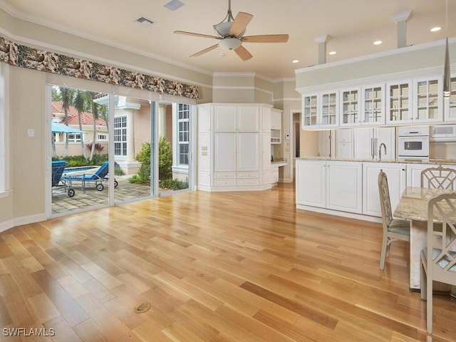 interior space with sink, crown molding, ceiling fan, and light wood-type flooring