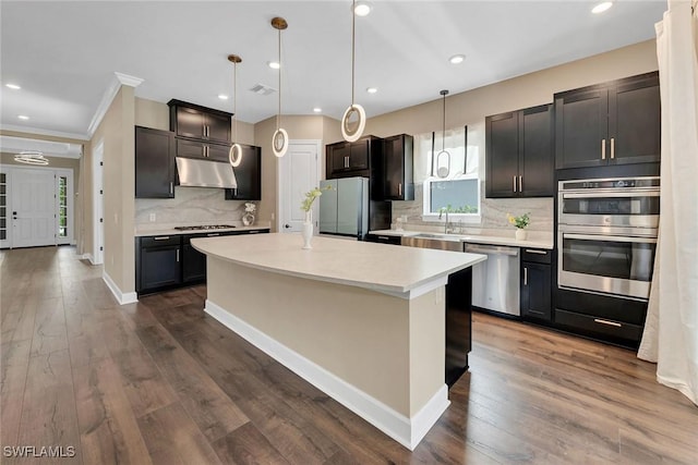 kitchen with pendant lighting, a center island, backsplash, and appliances with stainless steel finishes