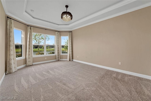 unfurnished room with a tray ceiling, light colored carpet, ornamental molding, and a water view