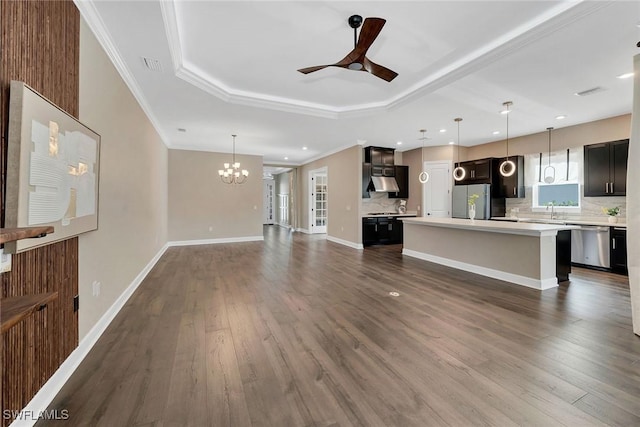 unfurnished living room with sink, dark hardwood / wood-style floors, crown molding, a tray ceiling, and ceiling fan with notable chandelier