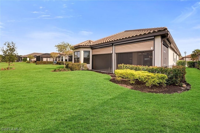 back of property with a sunroom and a yard