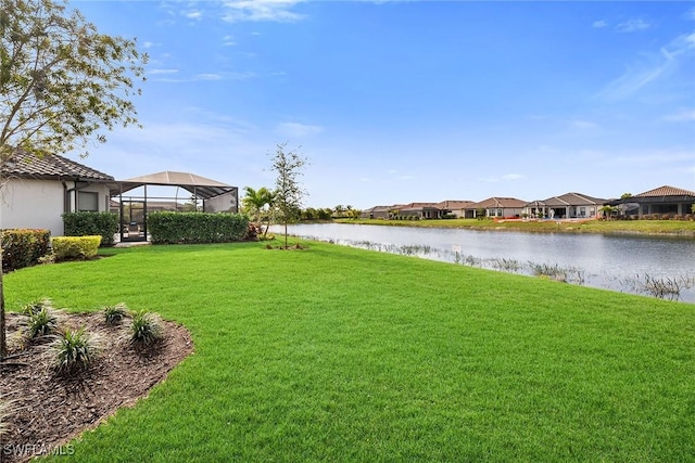 view of yard featuring a lanai and a water view