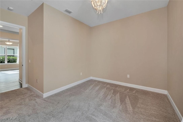 spare room featuring carpet flooring and a chandelier