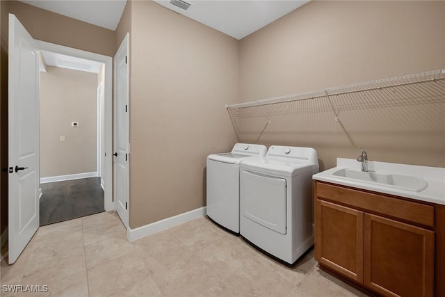 laundry area with washer and clothes dryer, light tile patterned flooring, and sink