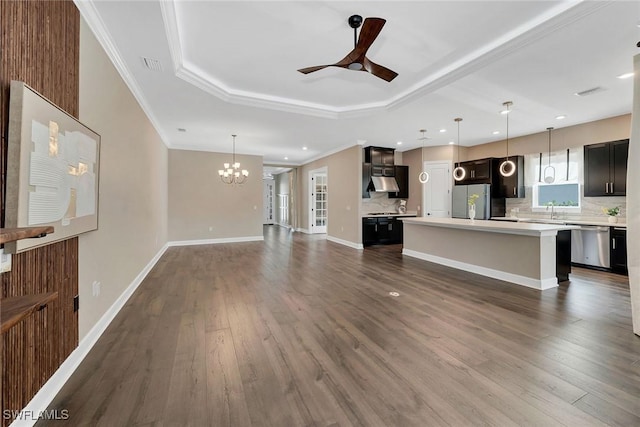 unfurnished living room featuring dark hardwood / wood-style flooring, ceiling fan with notable chandelier, ornamental molding, and a raised ceiling